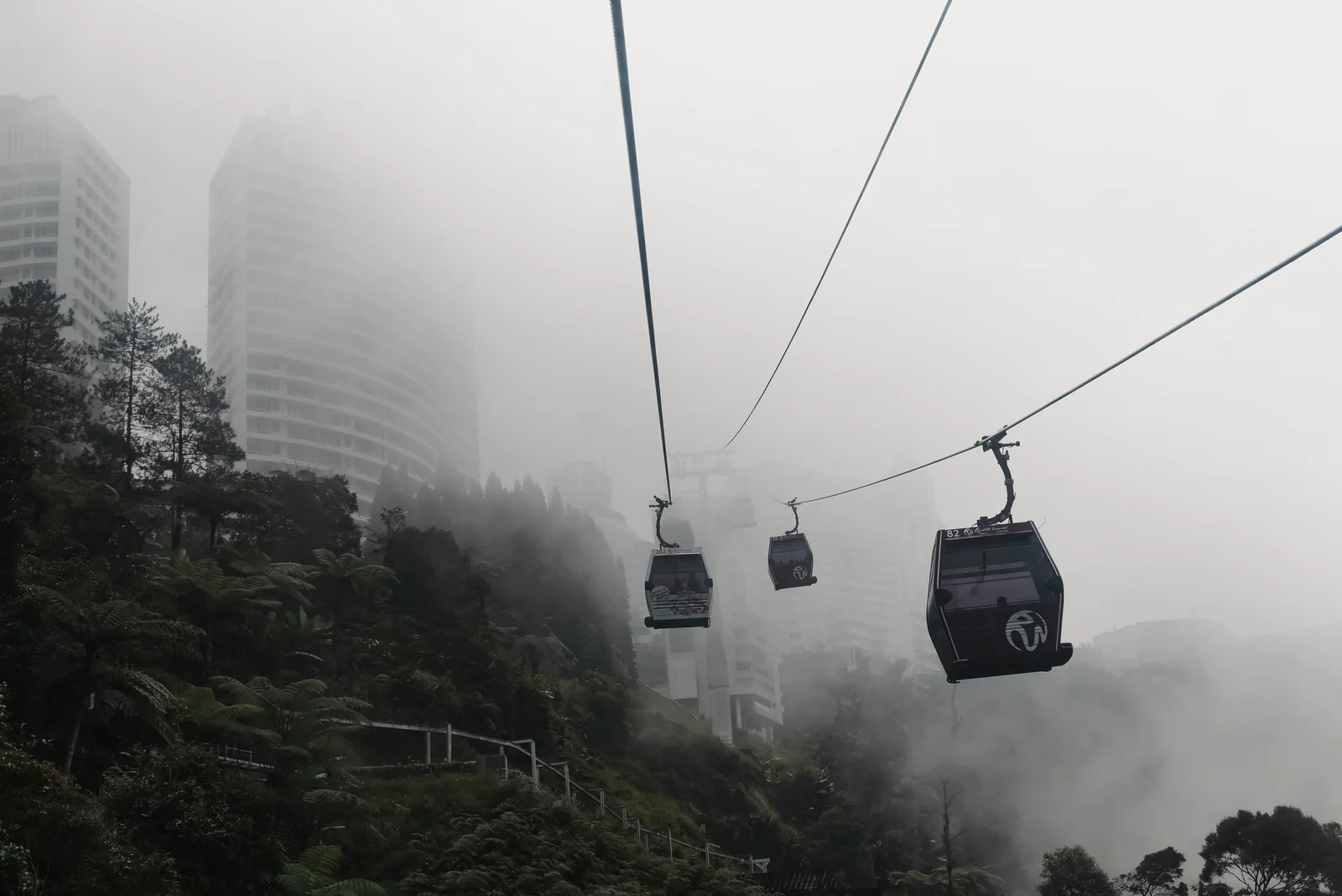 Cable cars gliding through fog over the hills