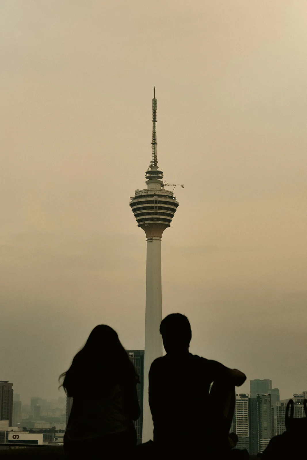A couple looking up at the KL Tower at dusk
