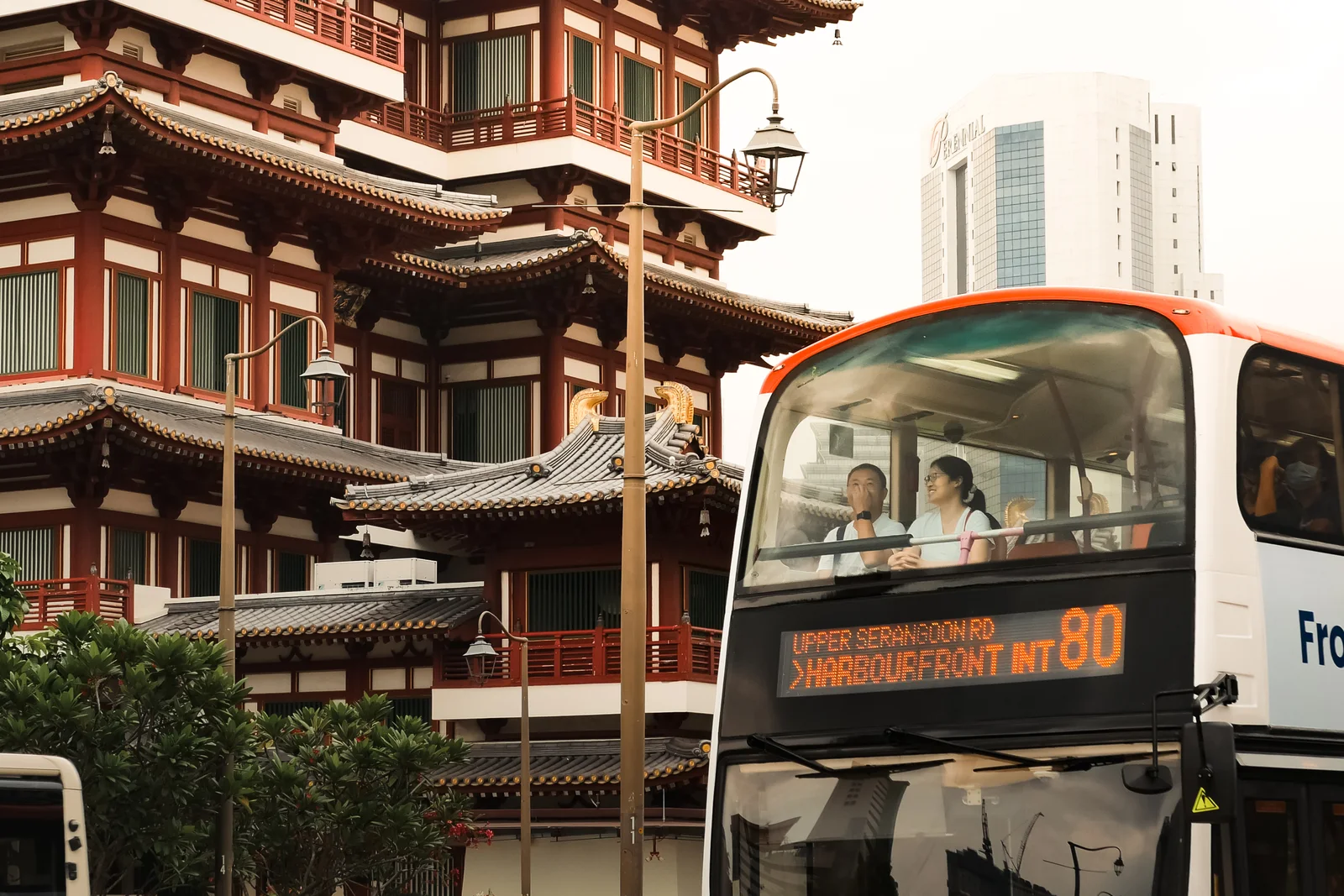 A double-decker bus passing rows of shophouses